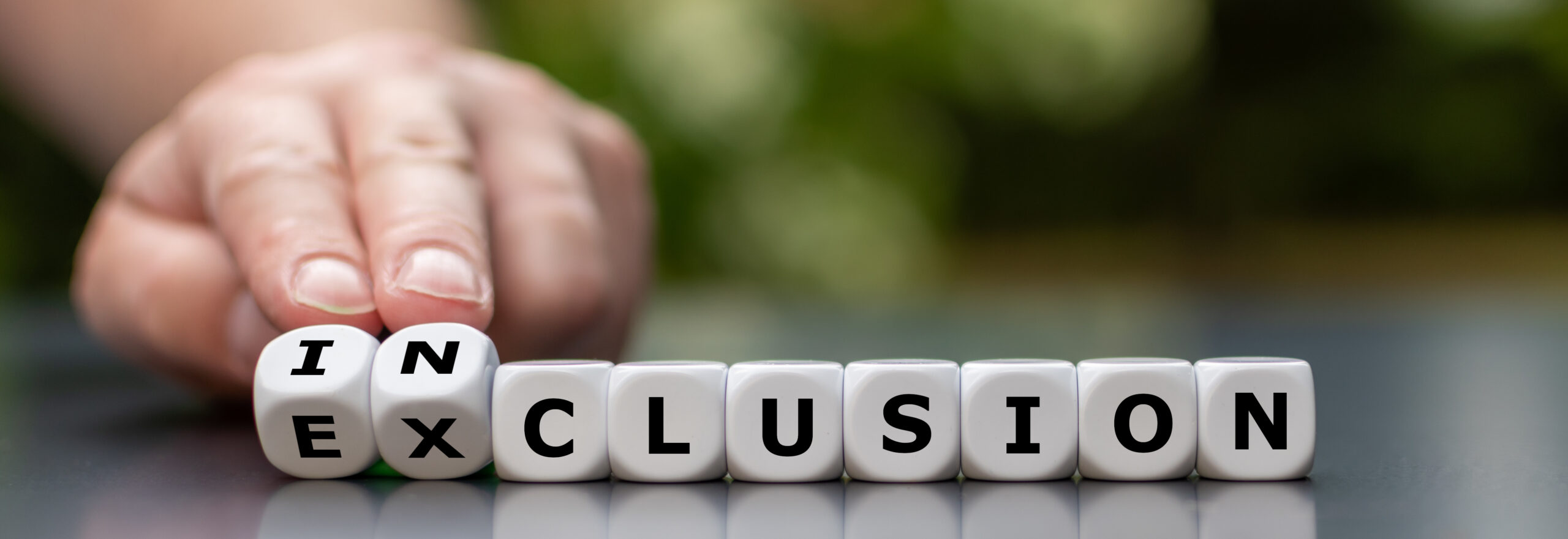 symbol for a better inclusion. hand turns dice and changes the word exclusion to inclusion.